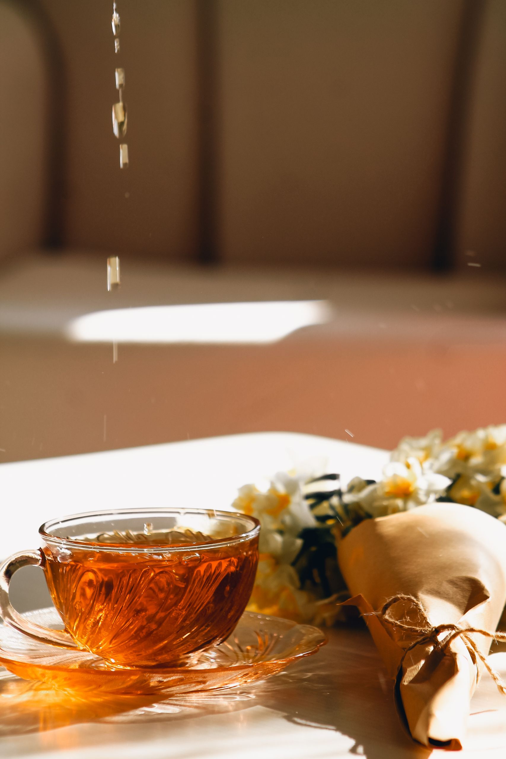 A glass tea cup with bouquet in warm morning light.