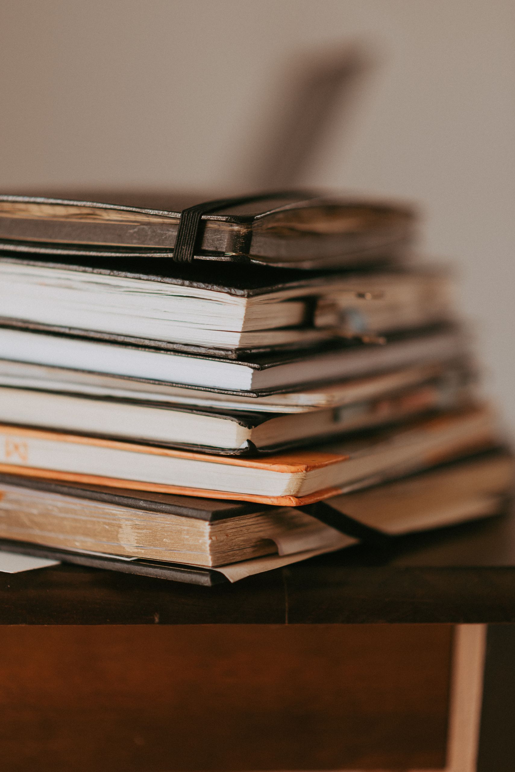 Close-up of stacked notebooks on a wooden table with warm lighting.