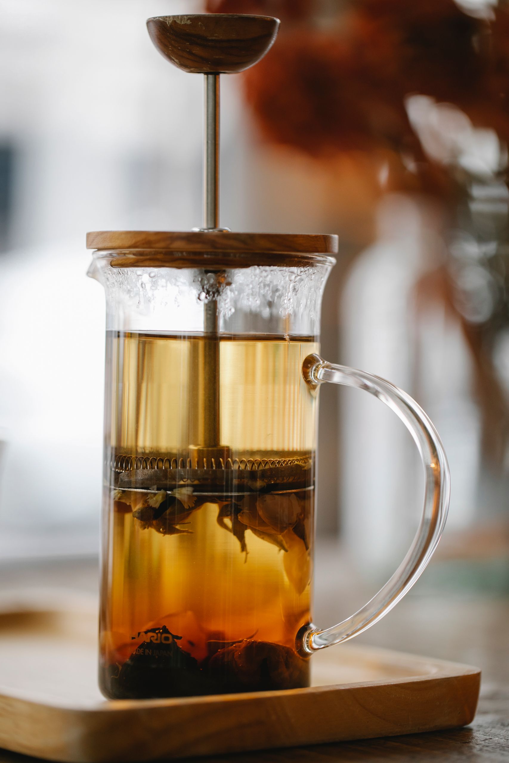 Fresh black tea brewing in glass French press teapot placed on kitchen table