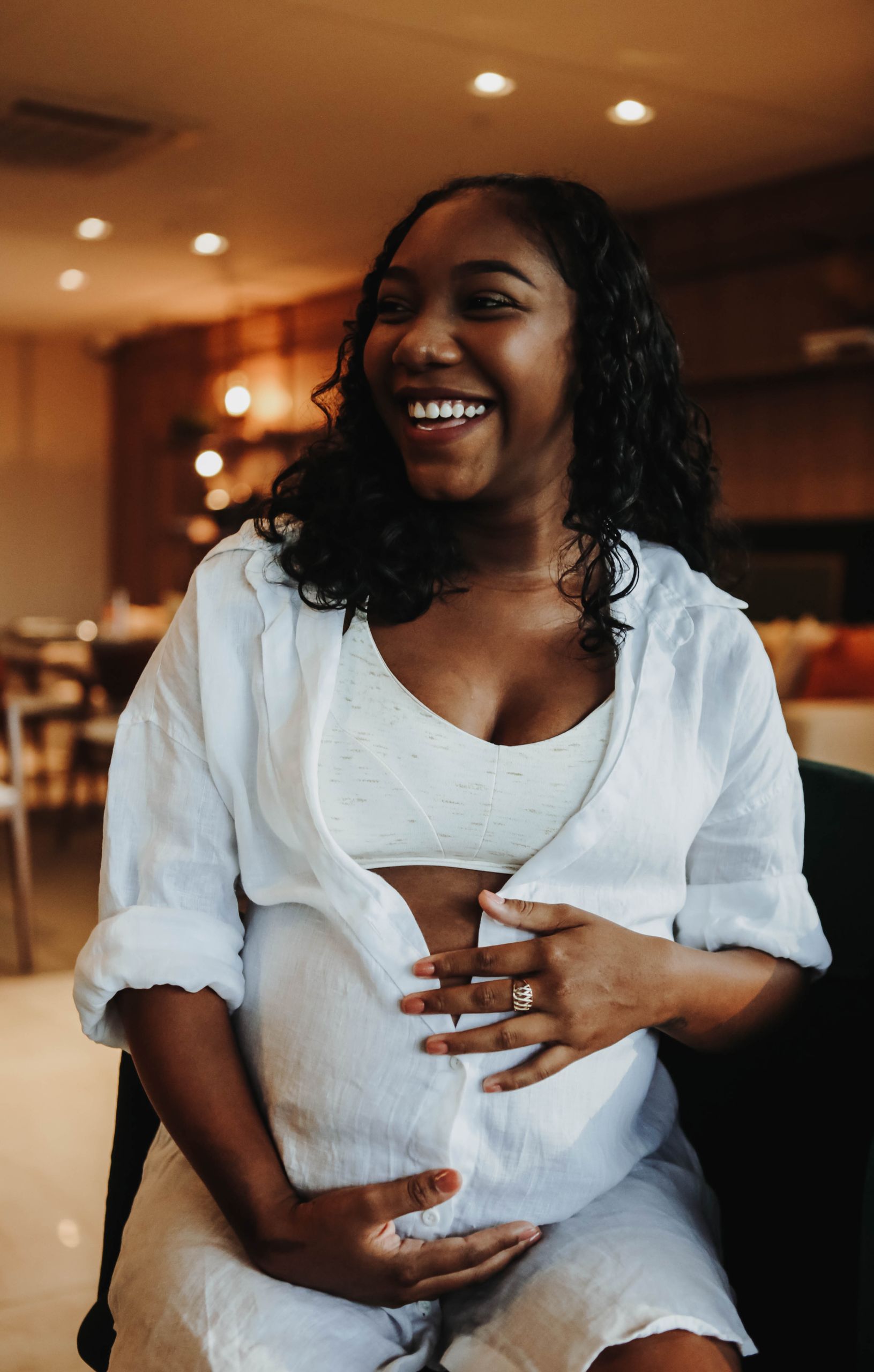Pregnant woman smiling warmly, embracing motherhood in cozy indoor environment.