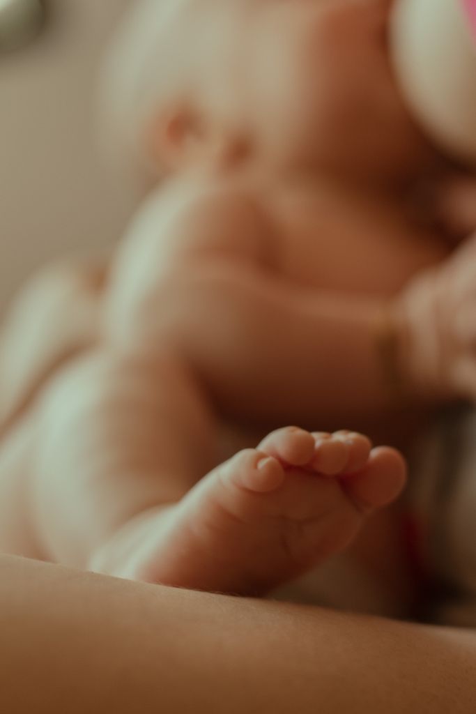 Tender close-up of a newborn's foot while nursing, conveying warmth and intimacy.