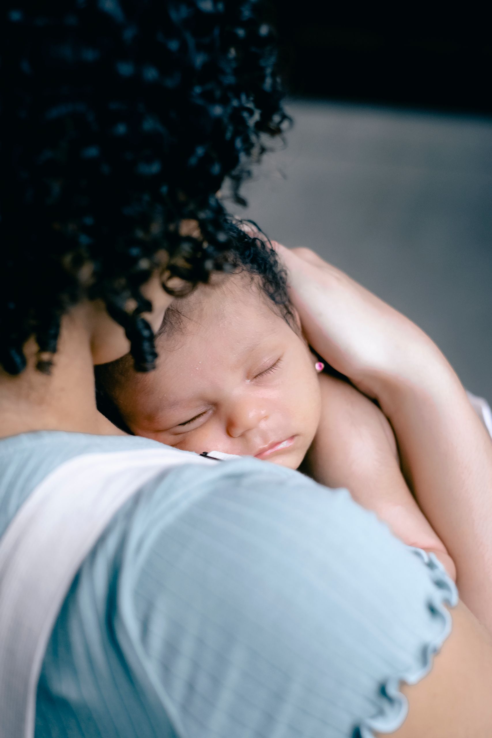Tender moment of a mother holding her sleeping baby, showcasing warmth and care.