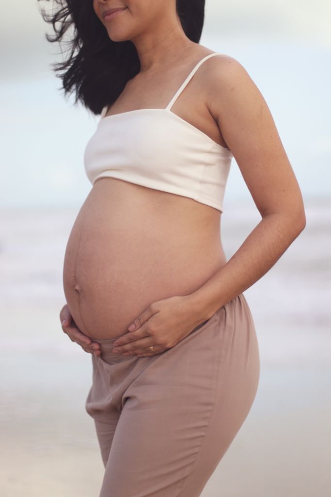A serene image of a pregnant woman on the beach, celebrating the joy of impending motherhood.