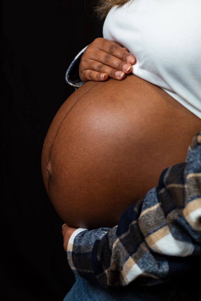 Close-up of a pregnant woman's belly with hands supporting it, symbolizing love and motherhood.
